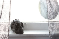 A clay skull on windowsill.